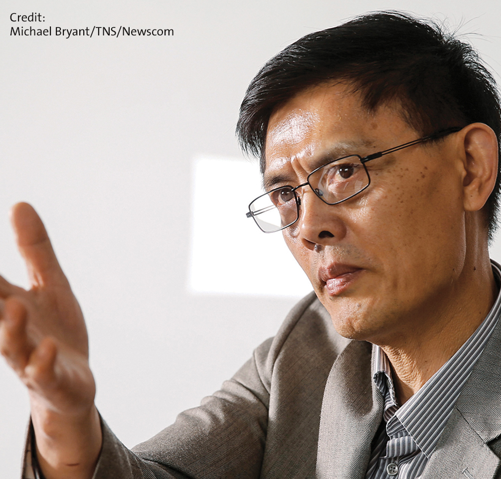 Promo image of physicist Xiaoxing Xi of Temple University. Xiaoxing has brown eyes, glasses, and short black hair, and is wearing a gray suit with a white and blue checked shirt.